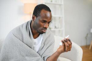 kalt und Grippe Behandlung. krank afrikanisch amerikanisch Mann mit Nasal- sprühen foto