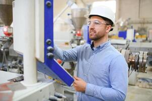 ein jung männlich Ingenieur inspiziert das Produktion von Plastik Fenster Frames foto