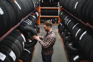 männlich Mechaniker halten Auto Reifen im Automobil Geschäft foto