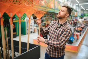 ein jung Mann im ein Gartenarbeit Ausrüstung Geschäft foto