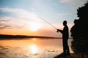 ein Fischer Silhouette Angeln beim Sonnenuntergang. frisches Wasser Angeln, Fang von Fisch. foto