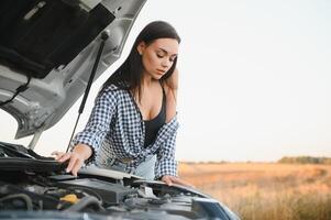schön sexy Frau in der Nähe von ein gebrochen Wagen. verwirrt Frau tut nicht kennt Was zu tun foto