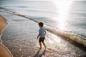 süß wenig Junge Laufen auf Strand und haben Spaß foto