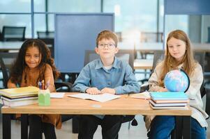 konzentriert gemischtrassig Studenten Kinder Schreiben Nieder Daten in Notizbuch während Sitzung beim Tabelle foto