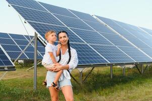 glücklich Mutter und ihr wenig Sohn sind Gehen in der Nähe von das Solar- Tafeln. das Konzept von Grün Energie. foto