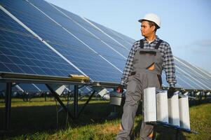 ein indisch männlich Arbeiter ist Arbeiten auf Installation Solar- Paneele im ein Feld foto