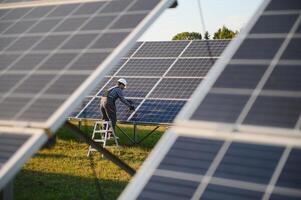 ein indisch männlich Arbeiter ist Arbeiten auf Installation Solar- Paneele im ein Feld foto