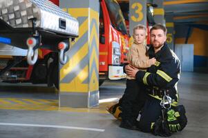 ein Feuerwehrmann nehmen ein wenig Kind Junge zu speichern ihn. Feuer Motor Auto auf Hintergrund foto