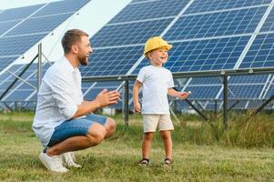 glücklich Vater und seine wenig Sohn sind Gehen in der Nähe von das Solar- Tafeln. das Konzept von Grün Energie. foto