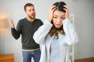 gereizt Mann ist schreien beim seine Ehefrau mit Gewalt. Frau ist Abdeckung ihr Gesicht mit Angst foto