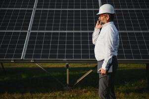 industriell Senior Mann Ingenieur Gehen durch Solar- Panel Feld zum Untersuchung foto