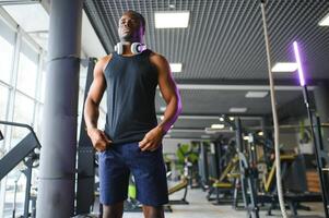 afrikanisch amerikanisch Mann Stehen auf Fitnessstudio Hintergrund foto