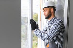 Arbeiter im Overall Installation oder einstellen Plastik Fenster im das Leben Zimmer beim Zuhause foto