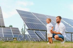 lächelnd Vater und seine wenig Kind auf Hintergrund von Solar- Tafeln. jung Vater genießen Ausgaben Zeit mit seine Sohn. glücklich Familie von zwei auf Hintergrund von Solar- Tafeln. foto