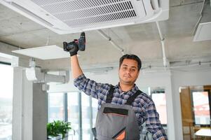 Porträt von jung männlich indisch Techniker reparieren Luft Klimaanlage. Luft Conditioner Instandsetzung. foto