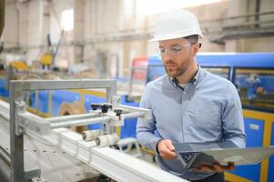 Ingenieur im Helm ist mit ein Laptop im ein schwer Industrie Fabrik foto