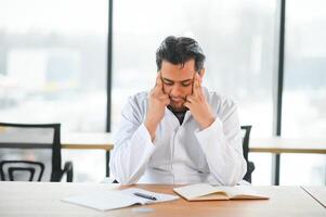 müde indisch Arzt Arbeiten im medizinisch Büro foto