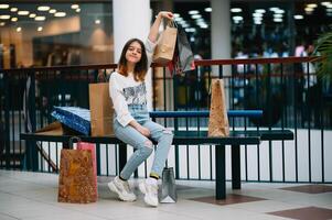 Einzelhandel, Geste und Verkauf Konzept - - lächelnd Teenager Mädchen mit viele Einkaufen Taschen beim Einkaufszentrum foto