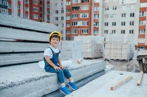 Architekt im Helm Schreiben etwas in der Nähe von Neu Gebäude. wenig süß Junge auf das Gebäude wie ein Architekt. foto