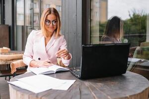 Porträt von jung attraktiv Geschäftsfrau Prüfung Papierkram im Bucht Licht Büro Innere Sitzung Nächster zu das Fenster, Geschäft Frau lesen etwas Unterlagen Vor treffen, gefiltert Bild foto