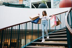 Einzelhandel, Geste und Verkauf Konzept - - lächelnd Teenager Mädchen mit viele Einkaufen Taschen beim Einkaufszentrum. Einkaufen Konzept foto