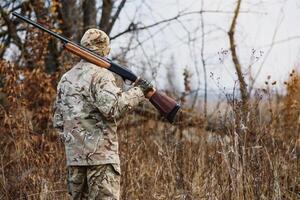 Jagd, Krieg, Heer und Menschen Konzept - - jung Soldat, Ranger oder Jäger mit Gewehr Gehen im Wald. foto