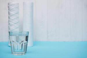 Wasser Filter. Kohlenstoff Patronen und ein Glas auf ein Weiß Blau Hintergrund. Haushalt Filtration System foto