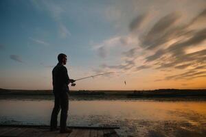 ein Fischer Silhouette Angeln beim Sonnenuntergang. frisches Wasser Angeln, Fang von Fisch. foto