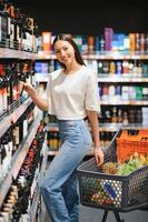 Mädchen wählt Wein im Supermarkt foto