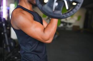 sportlich schwarz Kerl Herstellung Gewichtheben oder Powerlifting beim modern Fitnessstudio foto