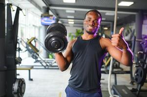 gesund afrikanisch Mann Arbeiten aus mit Hanteln im Fitnessstudio foto