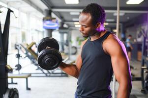 jung Mann Stärkung Bizeps mit Hantel im Fitnessstudio foto