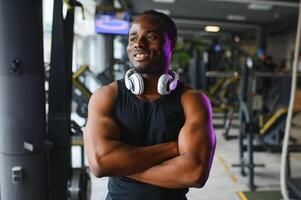 afrikanisch amerikanisch Mann Stehen auf Fitnessstudio Hintergrund foto