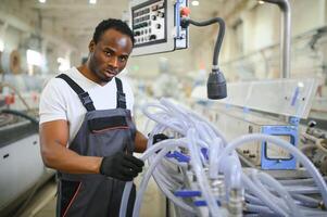 Porträt von afrikanisch amerikanisch männlich Ingenieur im Uniform und Stehen im industriell Fabrik foto