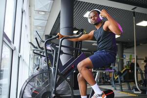 sportlich schwarz Mann tun Cardio trainieren auf Übung Fahrrad im Fitnessstudio. Konzept von Sport und gesund Lebensstil foto