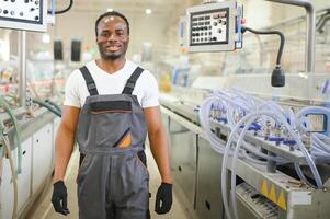 Porträt von afrikanisch amerikanisch männlich Ingenieur im Uniform und Stehen im industriell Fabrik foto