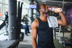 glücklich jung afrikanisch Mann Trinken Wasser nach Übung foto