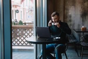 jung Geschäftsmann reden auf Handy, Mobiltelefon Telefon während Arbeiten auf Laptop im Cafe. foto