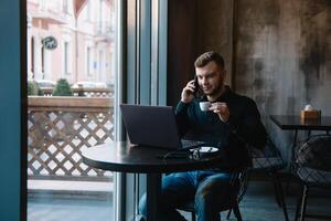 jung Geschäftsmann reden auf Handy, Mobiltelefon Telefon während Arbeiten auf Laptop im Cafe. foto