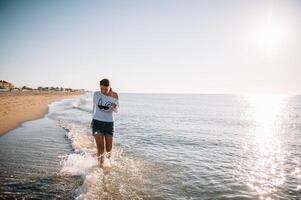 schön Mädchen mit ziemlich Beine Gehen entlang das Strand im das Sommer- heiß Tag in der Nähe von das Meer. foto