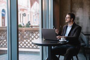 jung Geschäftsmann reden auf Handy, Mobiltelefon Telefon während Arbeiten auf Laptop im Cafe. foto