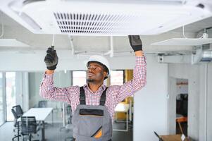 afrikanisch männlich Techniker reparieren Luft Klimaanlage. foto