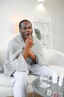 krank afrikanisch Mann mit Kehle sprühen beim Zuhause foto