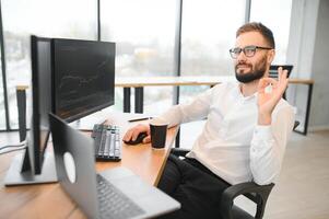 Krypto Händler sitzt beim seine Arbeitsplatz im Vorderseite von ein Monitor mit Diagramme. foto