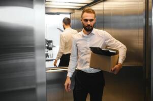 jung gut aussehend Geschäftsmann im Licht modern Büro mit Karton Kasten. zuletzt Tag beim arbeiten. verärgert Büro Arbeiter ist gefeuert foto