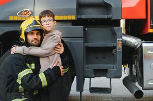 Feuerwehrmann halten Kind Junge zu speichern ihm im Feuer und Rauch, Feuerwehrleute Rettung das Jungs von Feuer foto