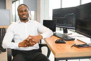 Afroamerikaner Makler funktioniert im Büro mit Arbeitsplatz und Analyse Technologie foto