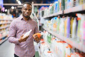 Mann im das Supermarkt im das Haushalt Chemikalien Abteilung foto