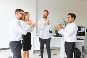 glücklich Geschäftsleute Lachen während zusammenarbeiten auf ein Neu Projekt im ein Büro. Gruppe von vielfältig Geschäftsleute Arbeiten zusammen im ein modern Arbeitsplatz foto