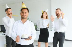 Überraschung. gemischt Rennen glücklich Menschen feiern ein Geburtstag von Kollege im das modern Büro foto